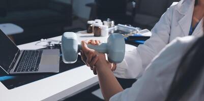 A woman is holding a dumbbell in front of a laptop photo