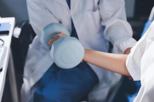 A doctor is holding a dumbbell while another person is sitting in a chair photo
