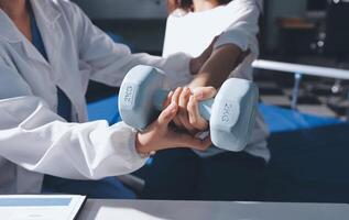 A woman is holding a dumbbell while a doctor is helping her photo
