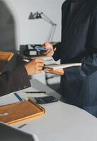 A man in a suit is signing papers while a woman is holding a clipboard photo