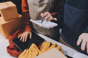 A woman is holding a pen and a clipboard while standing next to boxes photo