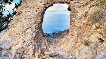 A stunning rock arch beautifully framing a serene ocean landscape, captivating during a breathtaking sunset video