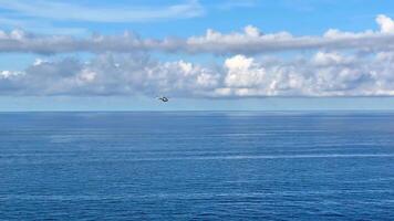 A calm sea stretches under a beautiful cloudy sky, featuring an intriguing aerial object hovering above the water video