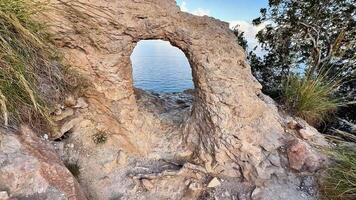 A stunning rock arch frames serene waters, a perfect spot for nature lovers and photographers to explore video
