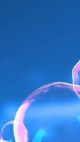 Close-up of colorful iridescent soap bubbles gently floating against a bright blue sky background video