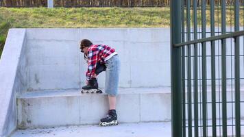 Stylish teenager waving while posing with inline skates in urban setting video