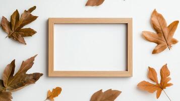 Wooden frame surrounded by autumn leaves on a white background offering a warm seasonal vibe photo