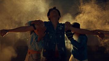 Three young adults dancing in a dusty, backlit environment, expressing freedom video