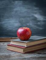 Desk With Apple and Stacked Books Beside Chalkboard in Classroom Setting photo