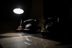 Old-fashioned Telephones and a Lamp Create a Nostalgic Atmosphere in a Dimly Lit Room, Showcasing Vintage Communication Tools photo