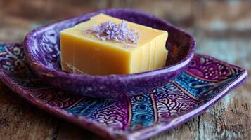 Natural Yellow Soap Bar Rests Elegantly in a Purple Ceramic Dish Adorned With Intricate Patterns and Textures photo