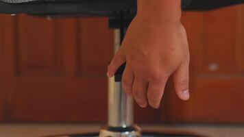 Close-up of an office chair's height adjustment lever, showcasing its mechanism and design against a wooden background. video