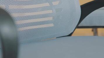 Close-up of a modern office chair with a mesh backrest and armrest, showcasing its ergonomic design and contemporary style. video