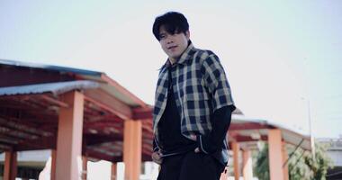 Handheld low angle view shot, Young Asian man dances with energy and cool moves in an outdoor multipurpose pavilion. Enjoy the rhythm and creativity. video