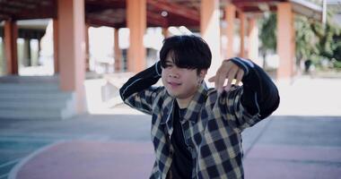 Handheld shot, Young Asian man dances with energy and cool moves in an outdoor multipurpose pavilion. Enjoy the rhythm and creativity. Solo dance. video