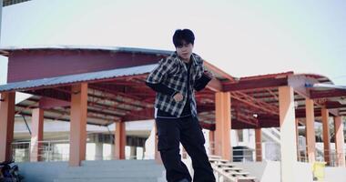 Low angle view shot, Young Asian man dances with energy and cool moves in an outdoor multipurpose pavilion. Enjoy the rhythm and creativity. Solo dance. video