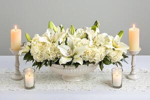 Elegant White Lily and Hydrangea Centerpiece with Candles. A serene and sophisticated floral arrangement perfect for weddings, memorials, or special events. photo