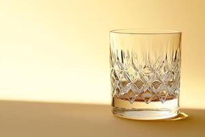 Elegant Cut Glass Tumbler on a Golden Background. A detailed close-up image of a crystal whiskey glass. photo