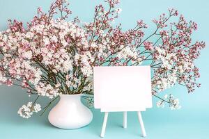 Blank Signboard Mockup with Delicate Spring Flowers in Vase. A pretty pastel-colored image perfect for spring promotions, websites, or blogs. photo