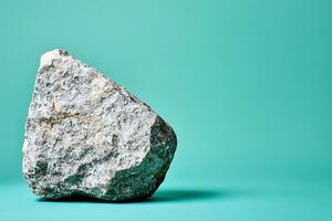Single Grey Rock on Teal Background. photo