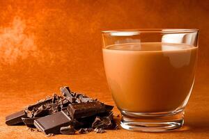 Delicious Chocolate Drink with Dark Chocolate Pieces. A tempting image of a glass of rich chocolate beverage next to a pile of broken dark chocolate squares. photo