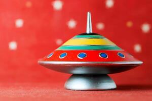 Retro Flying Saucer Top Toy on Red Background. A colorful spinning top shaped like a vintage UFO. photo