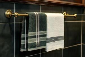 Elegant Bathroom Towels Hanging on a Gold Towel Rack Against Dark Tiles. photo