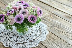 Delicate Pink and Purple Anemone Bouquet in Glass Vase on Rustic Wooden Table. photo