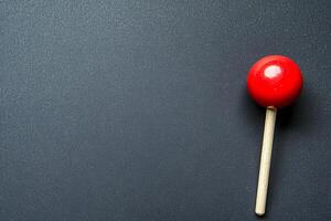 Single Red Ball on a Stick Against a Dark Gray Background. A simple image perfect for backgrounds, presentations, or design projects. photo