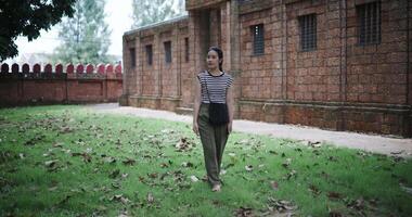 Young Asian woman walking around, admiring the natural scenery and ancient brick structures, Enjoy holiday travel. video