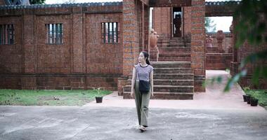 Handheld shot, Relaxed young woman walking around, admiring the natural scenery and ancient brick structures, Enjoy holiday travel. video