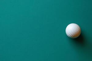 Single Golf Ball on Teal Background Copy Space for Sports Design. photo