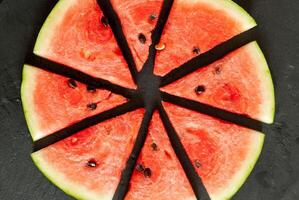 Watermelon slices cut into slices on a black slate photo