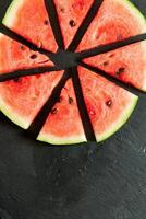 watermelon slices cut into slices on a black slate with copy space photo