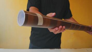 Person Holding a Rolled Document Against a Yellow Background video
