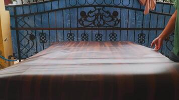 Person Handling Large Sheet of Material in Front of Decorative Gate video