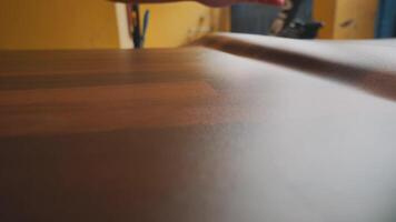 A close-up view of a hand smoothing a wooden surface, showcasing the texture and grain of the wood. The background is blurred, emphasizing the craftsmanship involved in woodworking. video