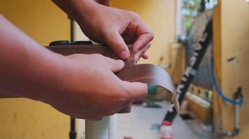 A close-up of a hand smoothing a wooden edge, showcasing craftsmanship. The background features a construction site with tools and materials. video