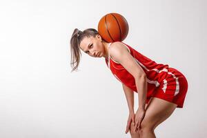 Female Basketball Player in Red Uniform Practicing Skills and Showing Determination on White Background photo