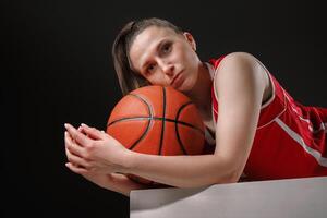 Female Basketball Player Resting with Ball after Game on Dark Background, Professional Sports Concept photo