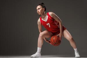 Focused Female Basketball Player Dribbling in Red Uniform during Professional Training or Competition photo