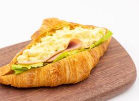 Smoked Ham Egg Salad Croissant on Wooden Board isolated on white background side view of Savory Breakfast or Lunch photo