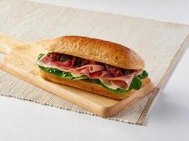 Parma Ham and Mozzarella cheese Sundried Focaccia Sandwich with Tomato and Pesto on a wooden board side view of lunch themes photo