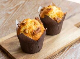 Two Delicious Pineapple Coconut Muffins Topped with Walnuts on wooden board Side View of Tropical Breakfast or Sweet Treat photo