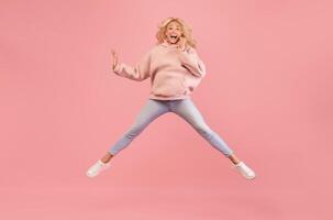 Wow offer. Full length portrait of surprised lady jumping, staring at camera, shocked by news or offer, isolated on pink studio background, free space photo