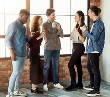 Business people having conversation during coffee break near window in loft office, copy space photo