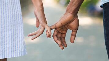 Loving couple holding little fingers while walking in park photo
