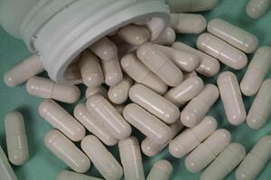 bottle of pills, some of which spilled onto a light blue surface 3 photo