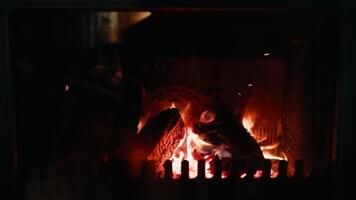 Warm orange flames consuming wooden logs in fireplace, casting soft glowing light and creating inviting ambiance during quiet evening hours. Blazing flames devour wooden logs. Perfect for background video