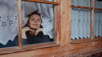 Playful woman framed in wooden window making silly face, playful vibe brightening cozy home atmosphere, playful energy perfect for lifestyle, positive emotion projects, inspiring authentic connection video
